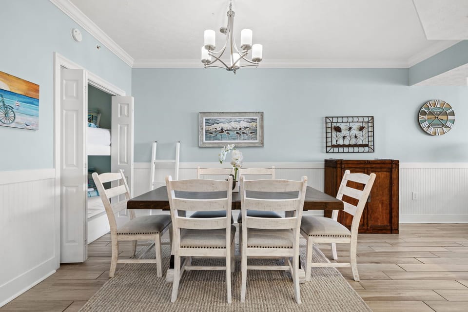 Gather around this beautiful dining table in your serene, coastal-inspired space. The soft blue walls and elegant lighting set the perfect mood for shared meals and memorable conversations.