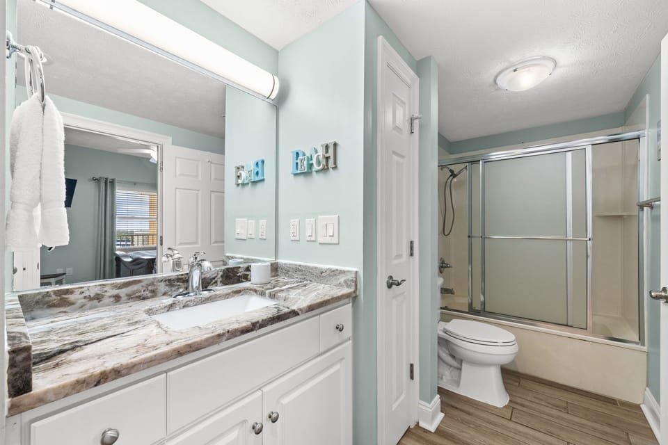 Modern bathroom with marble countertop and glass-enclosed shower