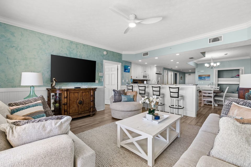 Sink into plush sofas with ocean-inspired accents and let the ceiling fan's gentle breeze cool you after sun-soaked beach days. Your open-concept haven blends comfort and coastal charm, perfect for gathering with loved ones.