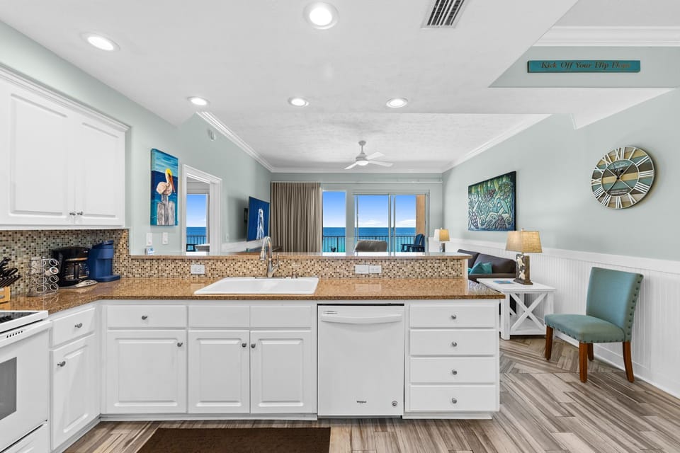 Modern kitchen with granite countertops overlooking a living area and ocean view.