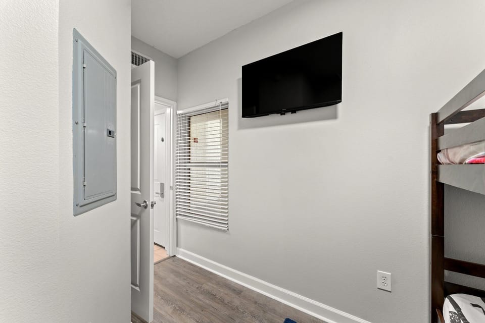 Compact room featuring a wall-mounted television and natural light from a window with blinds.