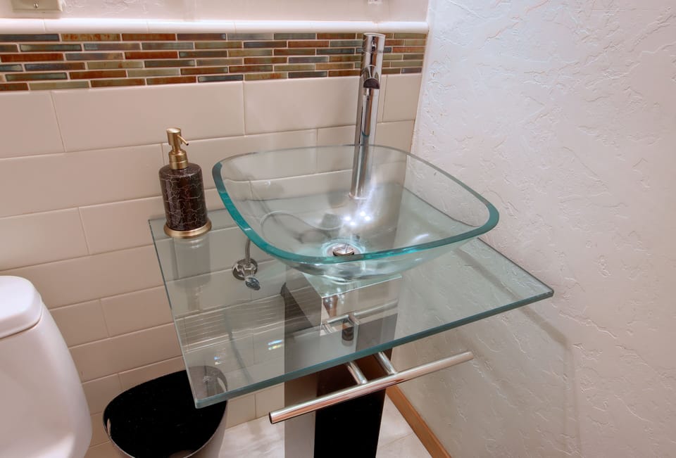Modern glass sink adds flair to the cozy half bath.