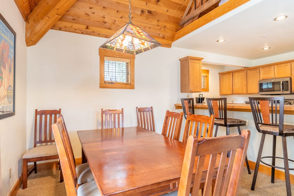 Gather around this warm dining space with rustic exposed beams overhead and a stylish stained glass light illuminating memorable meals with your group.
