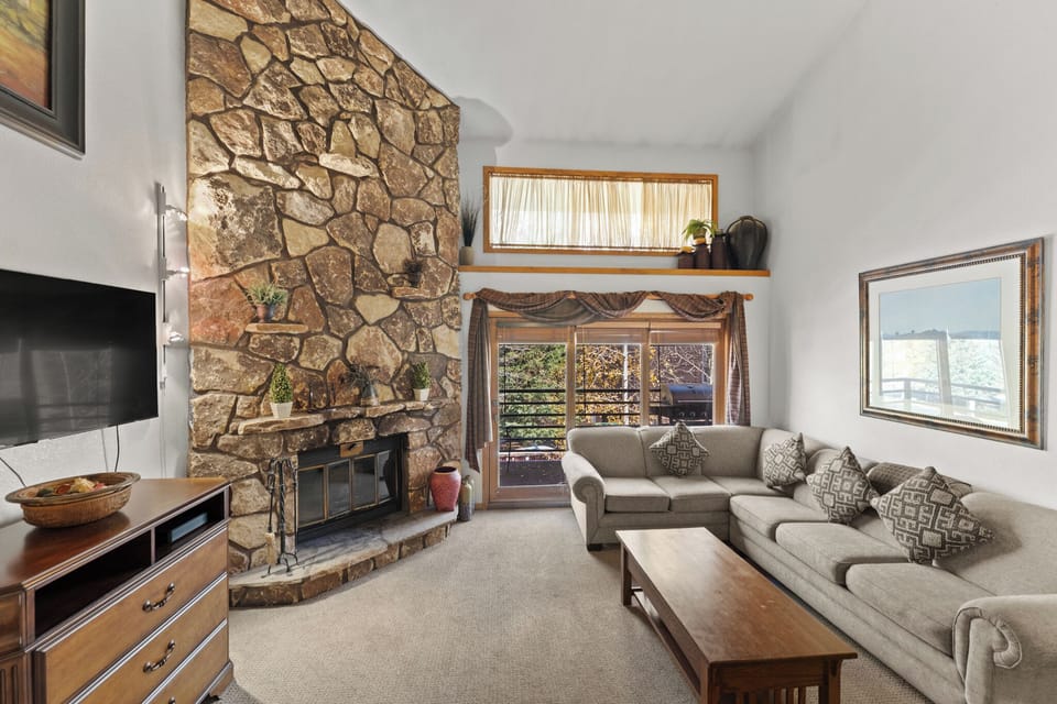 Sink into plush seating beside the stunning stone fireplace, where rustic charm meets modern comfort in your mountain retreat.