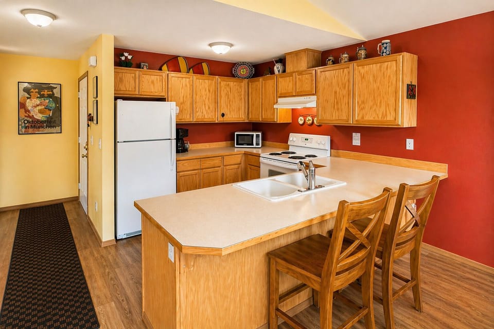 Your fully equipped kitchen features warm wood cabinets, modern appliances, and a breakfast bar where you can enjoy morning coffee.