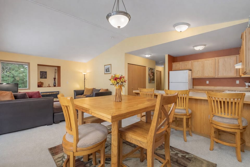 Your open-plan living space blends dining and kitchen seamlessly, with warm wood furnishings and comfortable seating perfect for memorable meals together.