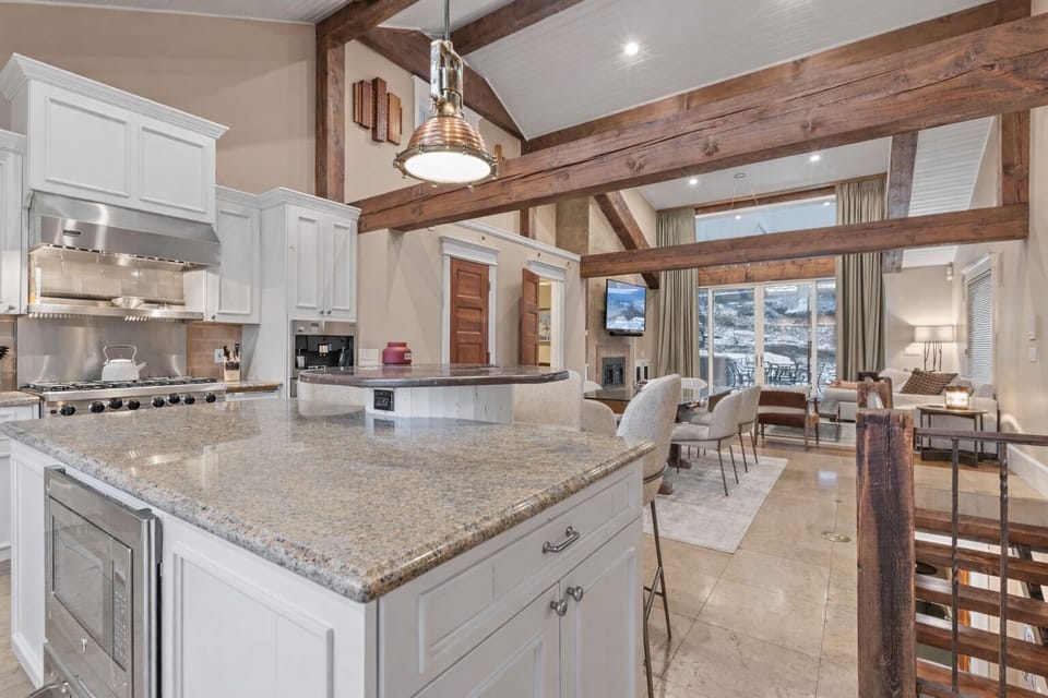 A stunning open-concept space where your group can gather around the gourmet kitchen island, sharing meals beneath rustic wood beams, then relax in the cozy living area with mountain views.