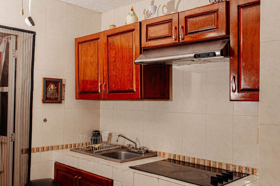 Kitchen with electric stove, refrigerator, blender, microwave, and more. 