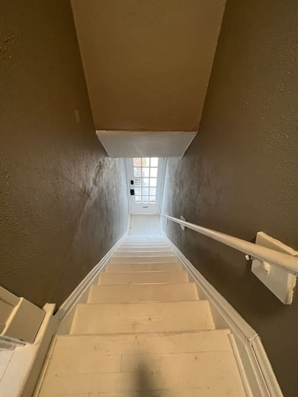 Access to second-floor Unit A requires a full interior flight of painted stairs with a wall-mounted handrail.