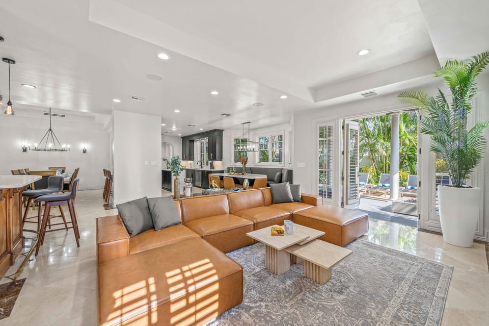 The family room features an 85” smart TV and wrap around sofa right off the patio.