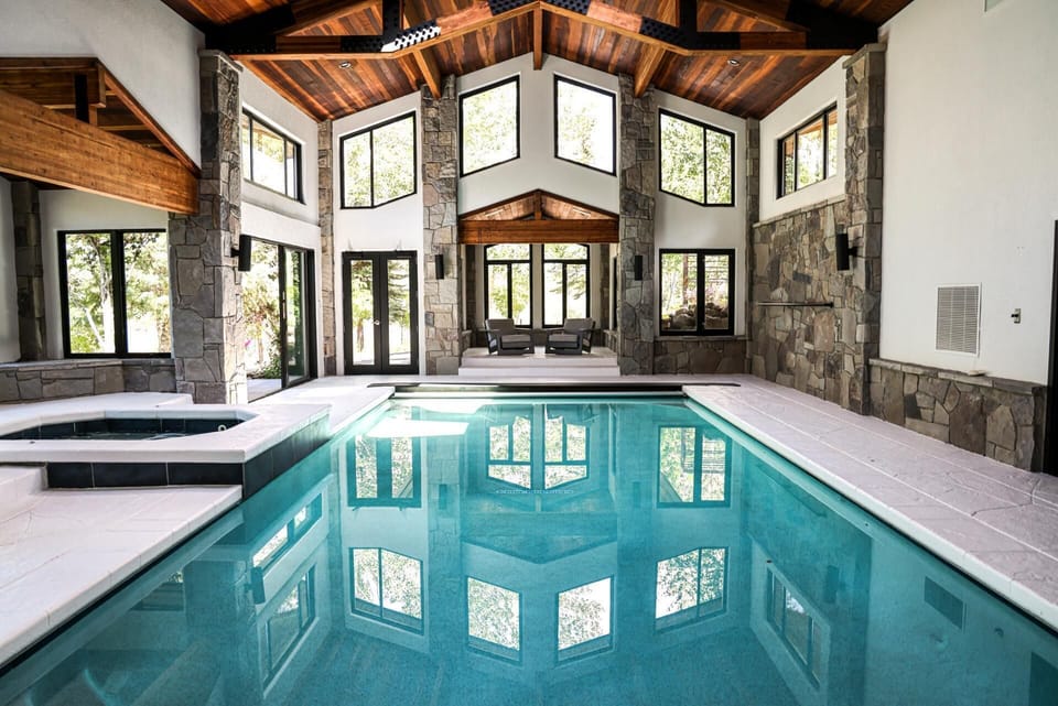     Luxury indoor pool oasis with stone accents and vaulted ceilings.
