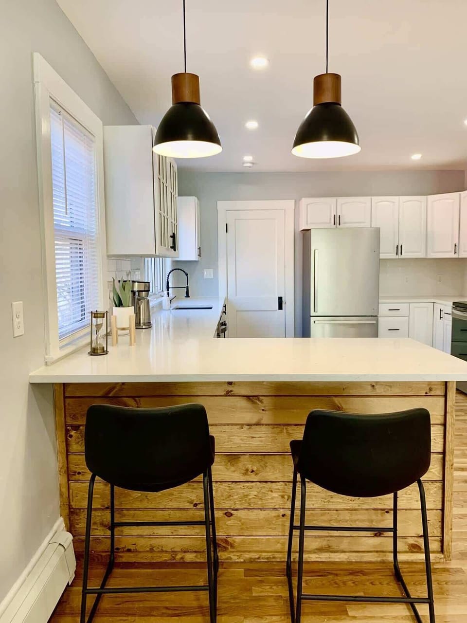 Kitchen: Front view of a wide peninsula with quartz countertops and soft lighting. Perfect for breakfasts. 