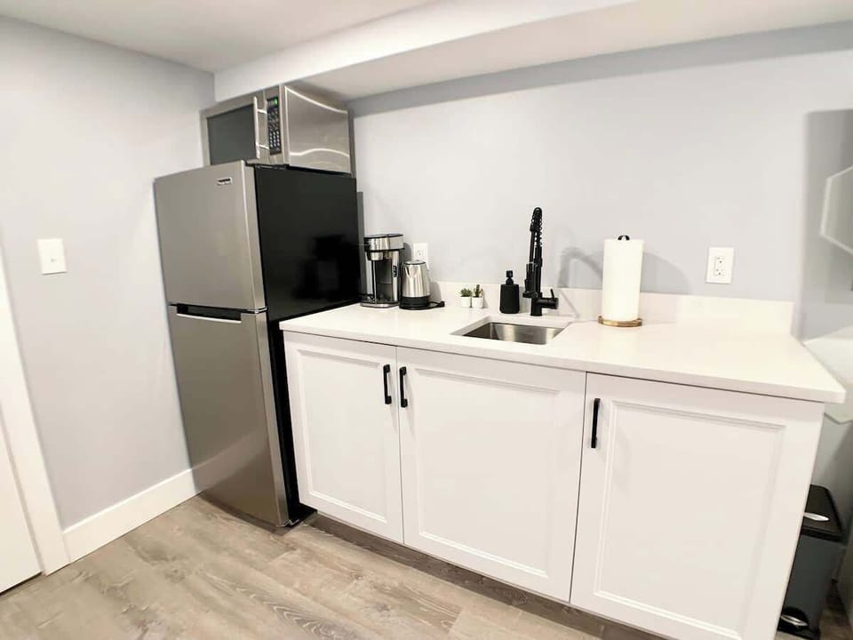 Opposite view of the kitchenette, featuring a full size fridge with a stainless steel microwave. 