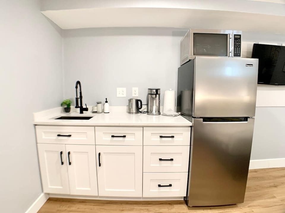 Front view of the kitchenette, featuring a full size fridge with a stainless steel microwave. 