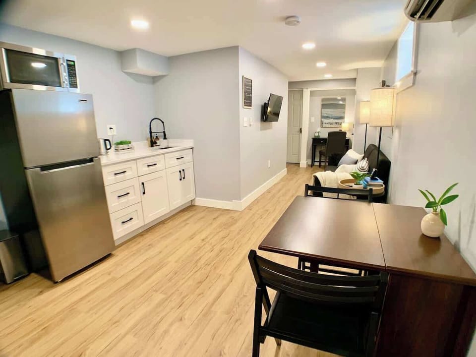 Corner view of the kitchenette, featuring a full size fridge with a stainless steel microwave and an extendable dining table. 