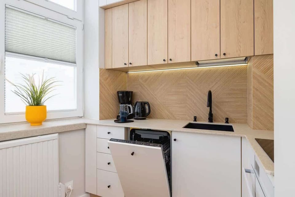 A compact kitchen with white cabinets, wooden countertops, and integrated appliances, maximizing space and functionality.
