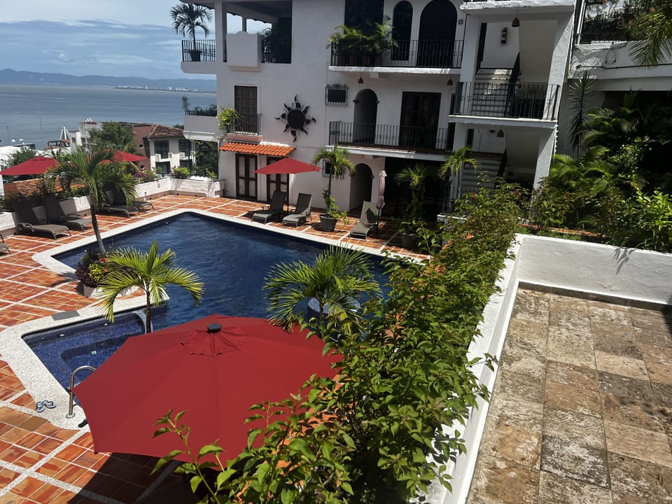 Look down on large main pool area.  Two cabanas, umbrellas and loungers.