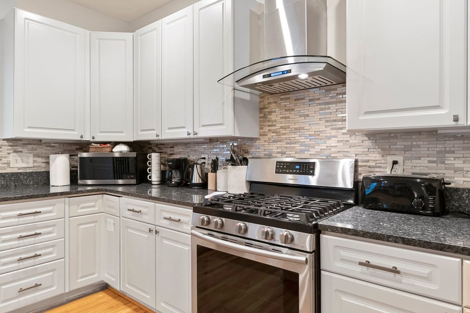 Furnished kitchen with stove, oven, and exhaust along with a microwave.