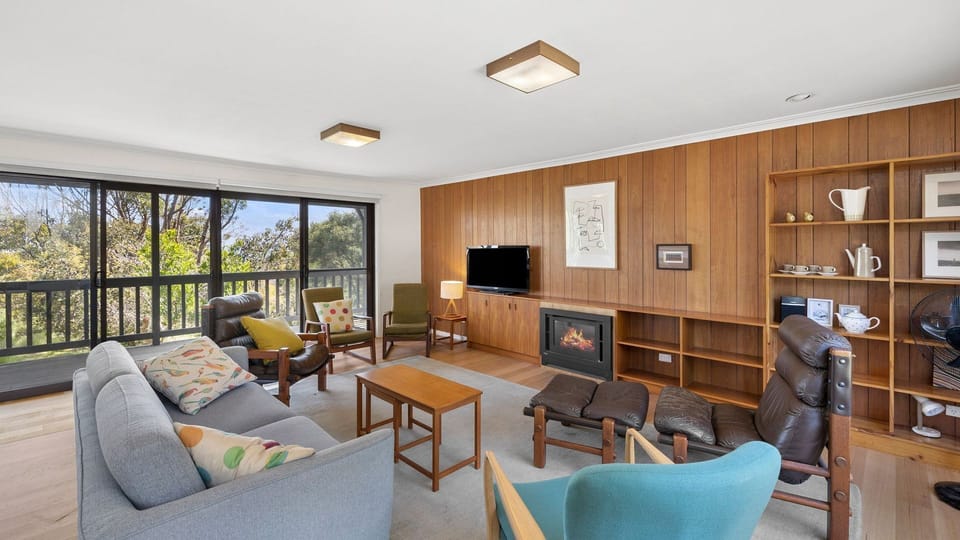 A stylish and elegant living room welcomes you. It has timber floors complemented by wooden shiplap walls. Adding to its artsy and cosy vibe, it has mismatched lounge chairs and couches, coloured throw pillows, Wi-Fi, and a flat-screen TV.
