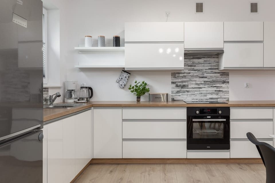 A sleek kitchen with white cabinetry, modern appliances, and a clean design.
