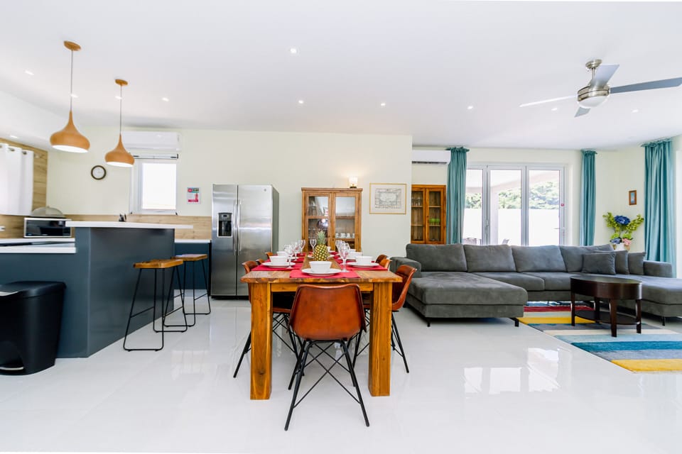 Graceful Living and Dining Area of the 4BR Home in Noord Aruba - Spacious open-plan design for a modern feel. - Ample natural light through large windows. - Elegant Decor - Vibrant foliage creating a serene atmosphere