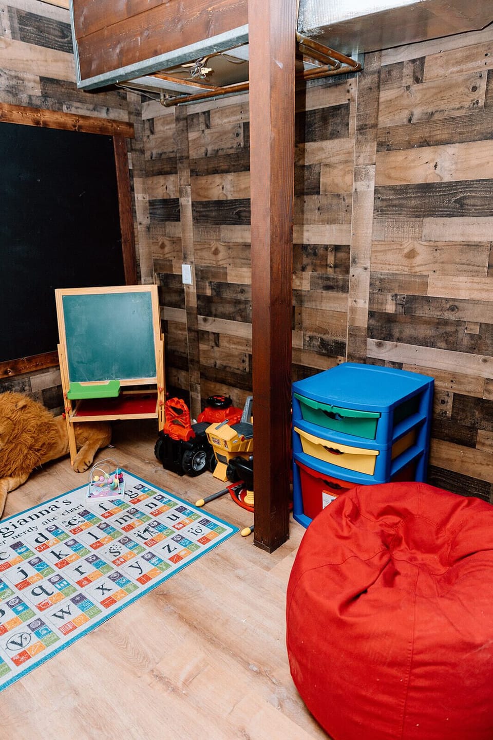 Dedicated playroom with toys, bean bags, chalkboard, and learning rug.