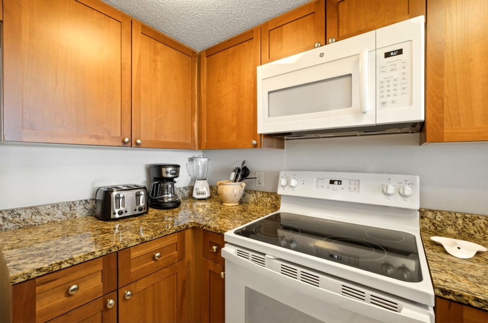 Ocean Breeze W 105- Your kitchen comes fully equipped with everything you need to prepare meals during your stay, including a stove, microwave, and coffee maker, all set against warm wood cabinetry and granite countertops.