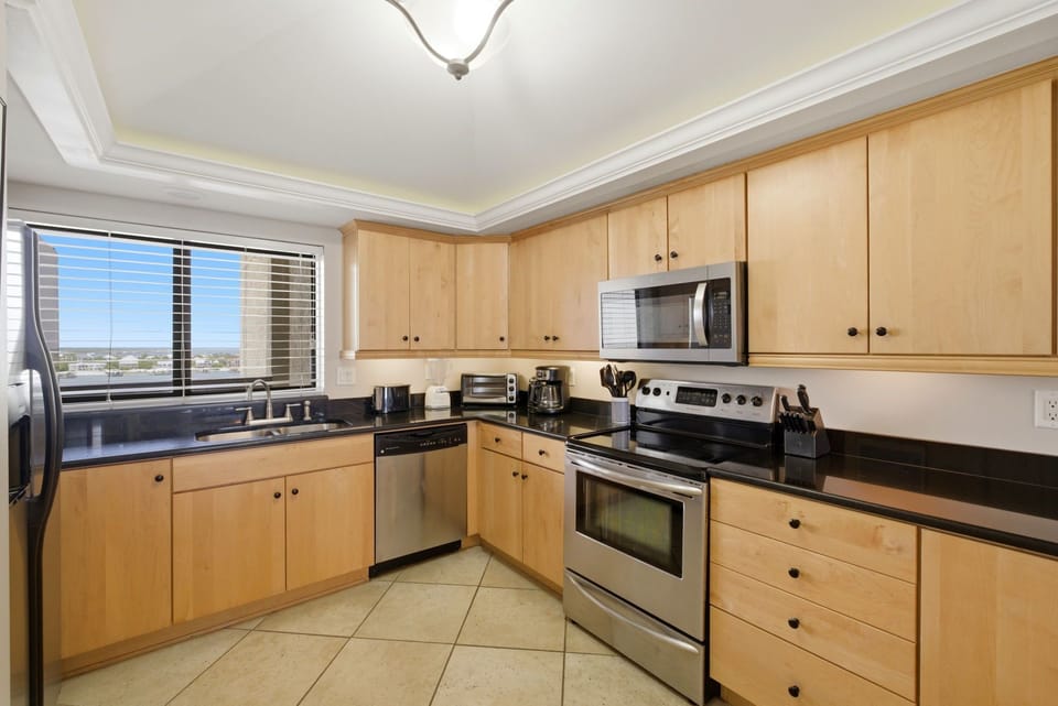 Shipwatch D803- Your modern kitchen features sleek stainless appliances, warm maple cabinetry, and a spacious layout perfect for preparing meals while taking in mountain views through the window.