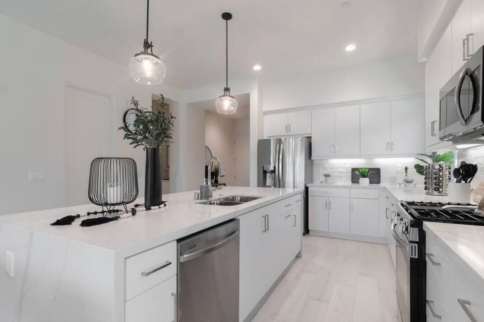 Modern white kitchen w/ pendant lighting, ample counter space & clean finishes
