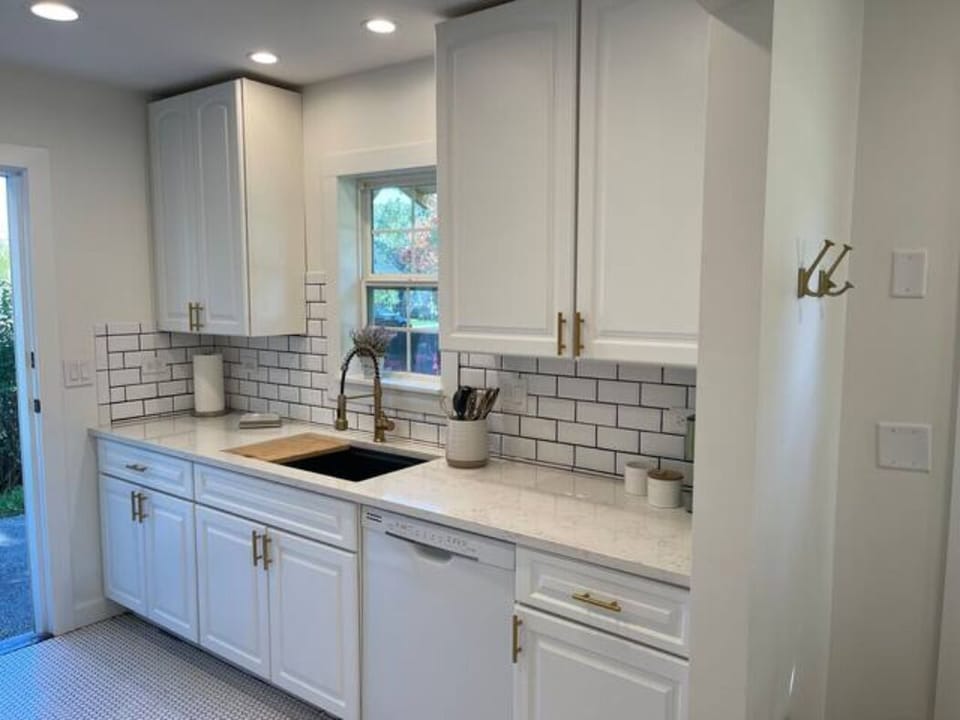 Kitchen sink with subway tile and penny round flooring.