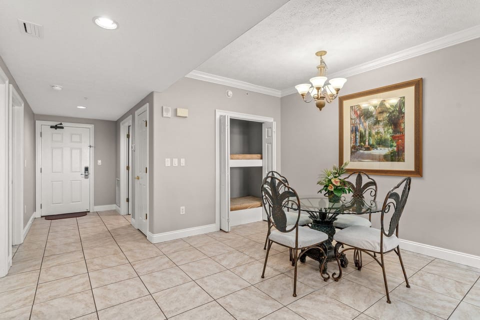 dining area with wrought iron chairs and a glass table under a chandelier
