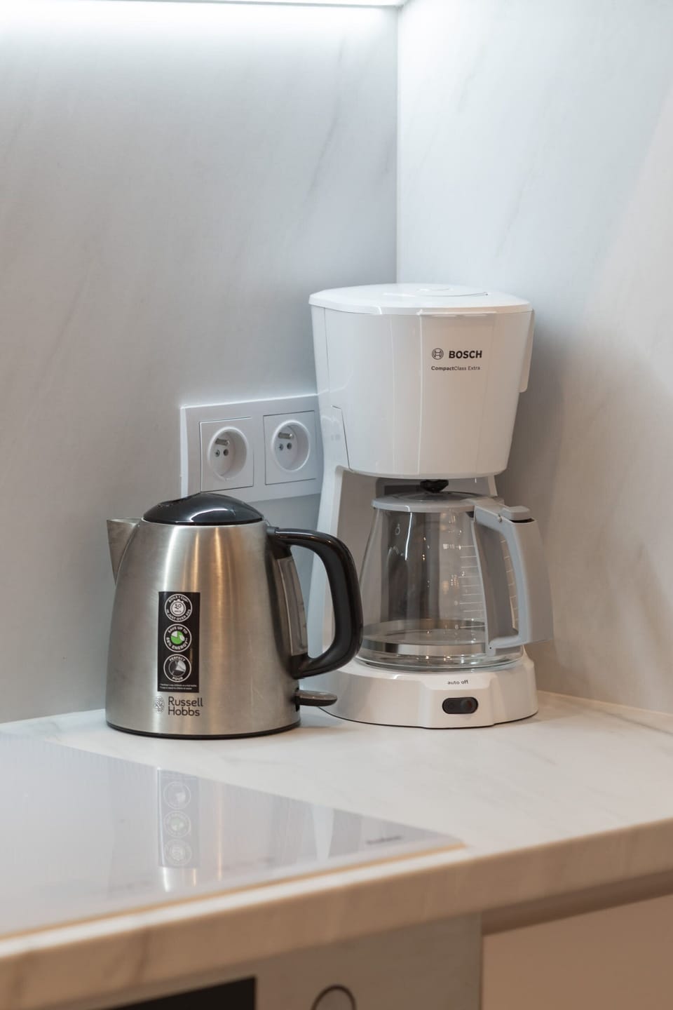 A coffee corner featuring a white coffee maker, cups, and a clean minimalist design.