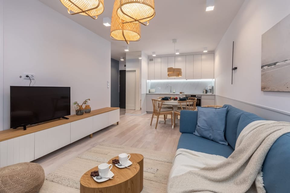 A living room with a cozy blue sofa, a wooden coffee table, and a warm lighting fixture creating a homely ambiance.