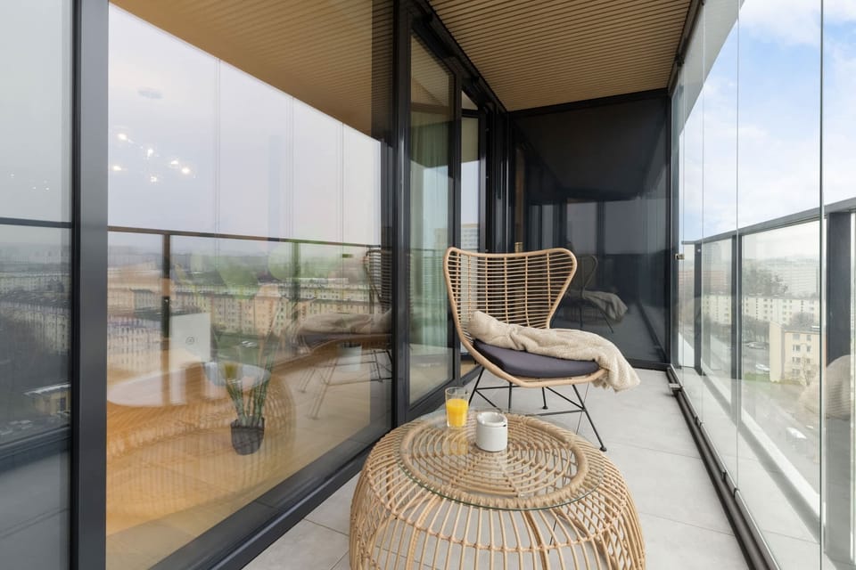 A glass-walled balcony with cozy furniture, offering panoramic views.
