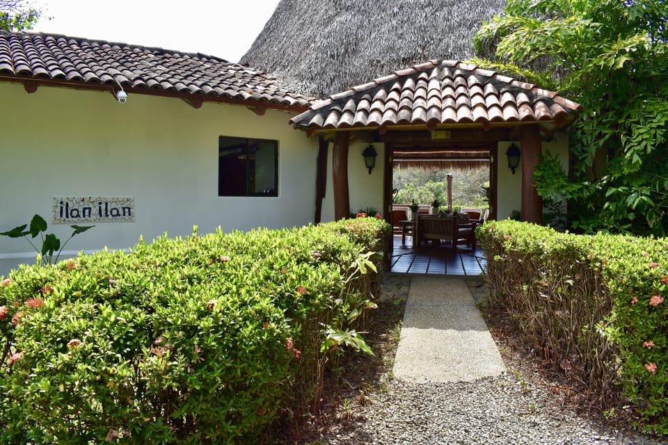 Private villa entrance with lush landscaping and open-air living beyond