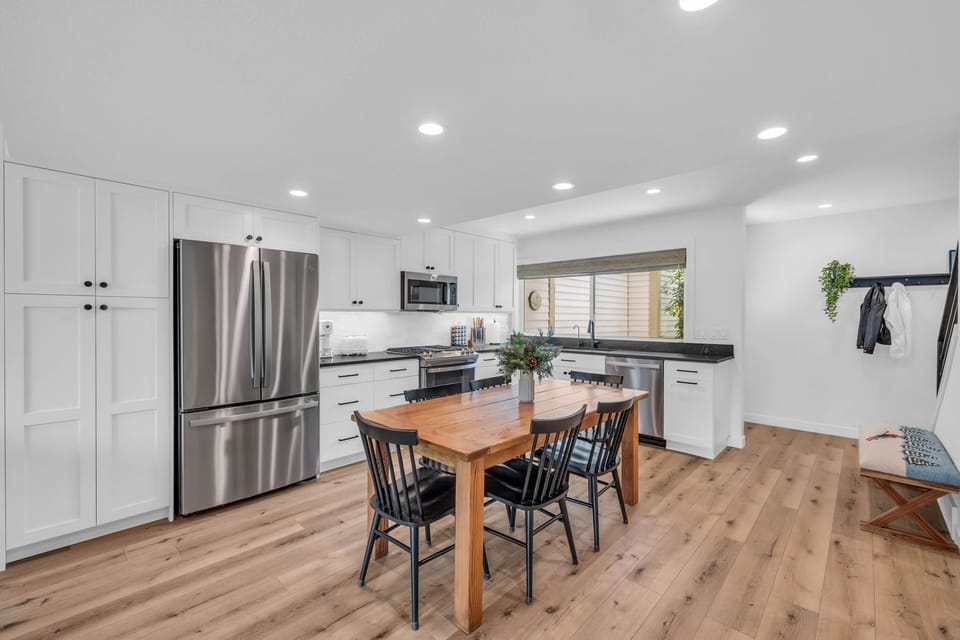 The kitchen and dining area is a dazzling space with a modern look featuring white cabinets, stainless steel appliances, and a beautiful wooden dining table with seating for 6.