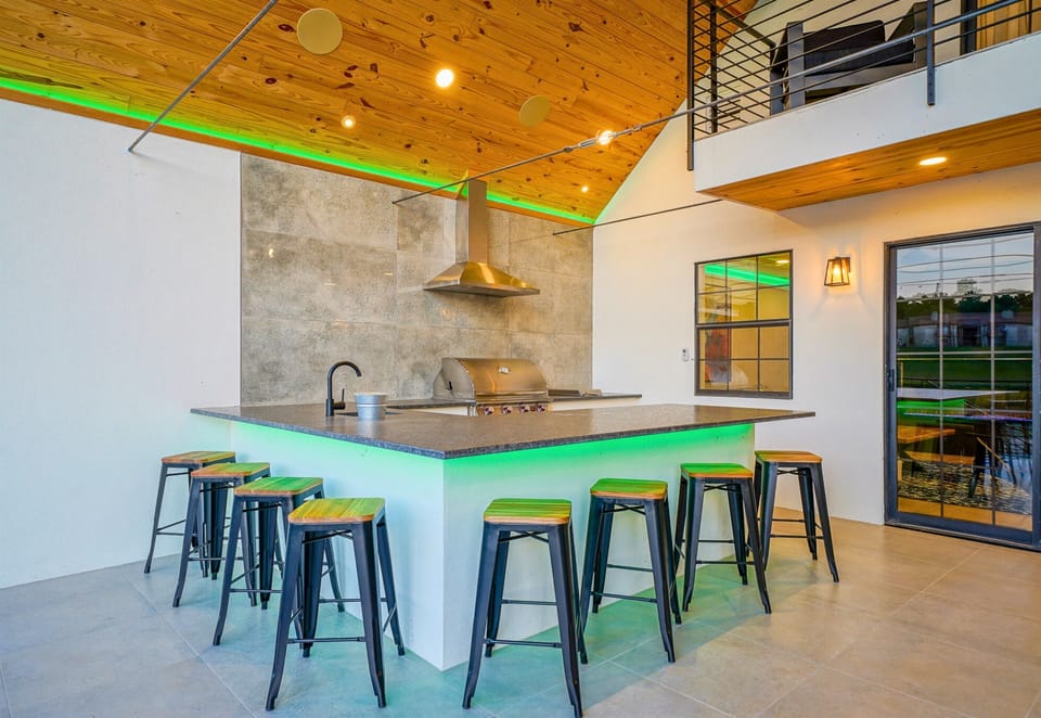 Grill in style with this covered outdoor kitchen featuring a bar, seating, and all the essentials for lake day feasts.