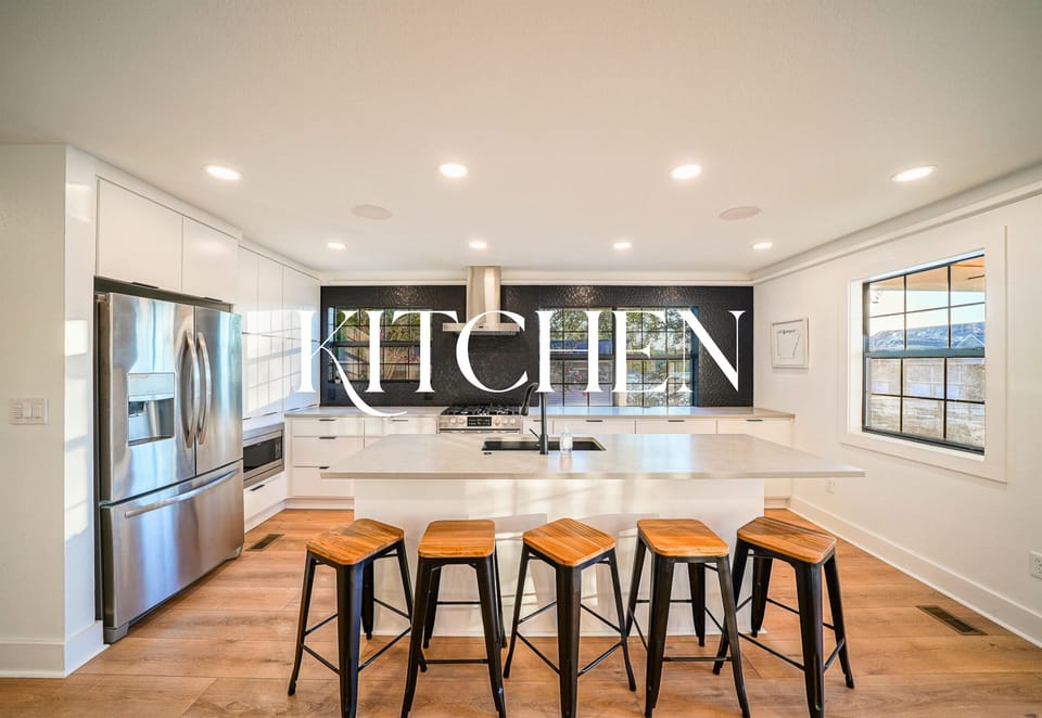 This stunning kitchen features a massive island, black tile backsplash, and chef-ready appliances — ideal for hosting in style.