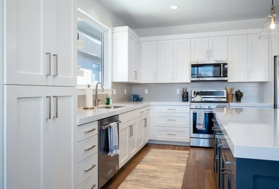 With its modern lighting, windows, quartz countertops, and stunning backsplash, the kitchen makes preparing dinner a truly enjoyable experience.