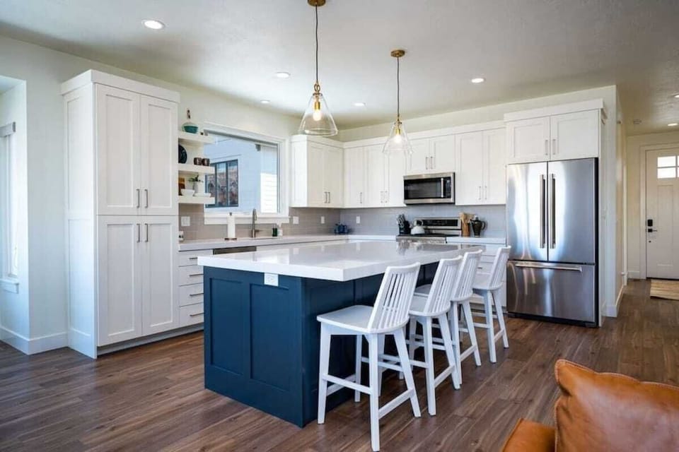 The gourmet kitchen features an island with seating for four and is equipped with stainless steel appliances, including a microwave, gas stove, and spacious refrigerator.