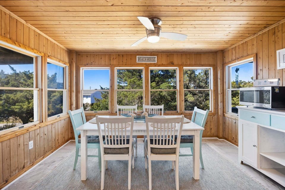 Just off the kitchen, the bright sunroom doubles as a dining area, featuring wood-paneled walls and large windows that fill the space with natural light—perfect for enjoying meals at sunset.