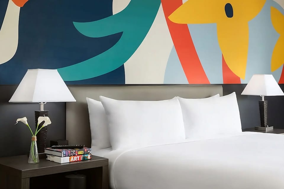 Unwind under bold art with plush pillows and bedside lighting.