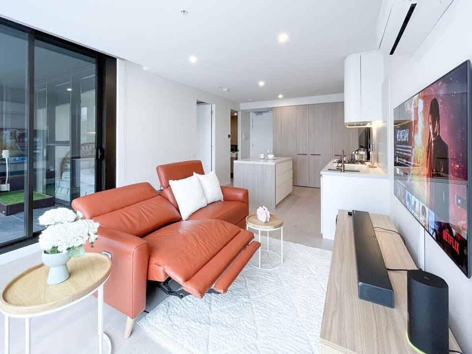 Bright living room features luxury leather electric recliner sofa and large smart TV