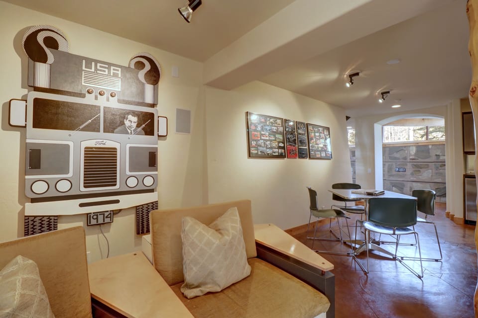A seating area with cushioned benches and a wall featuring truck-themed art on the left, and a small dining area with chairs and a table near photo displays on the right.