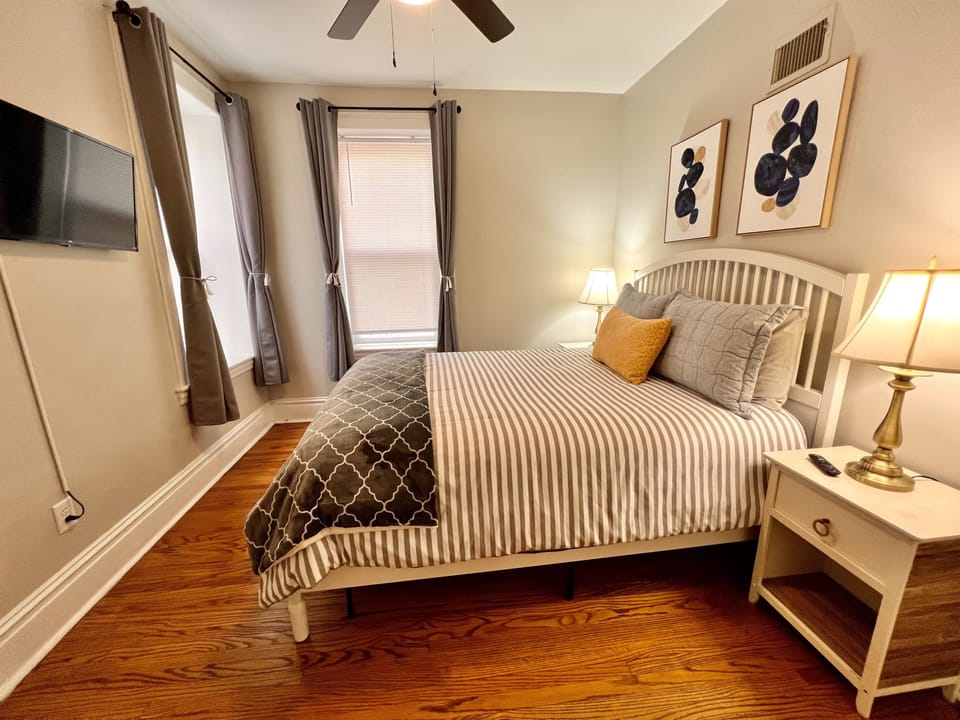 Main bedroom with plush queen bed and Roku TV and blackout curtains.