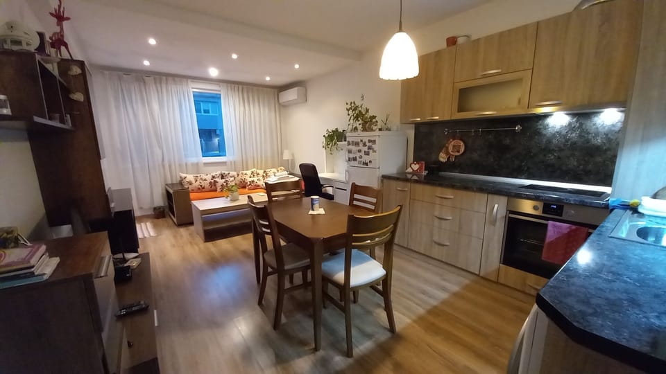 Dining space with four massive wood chairs, just between the TV and the kitchen