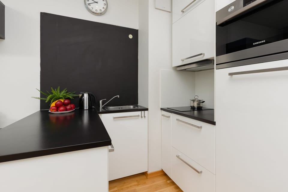 A sleek, modern kitchen with black countertops, white cabinets, and stainless steel appliances, offering a minimalist yet functional layout.