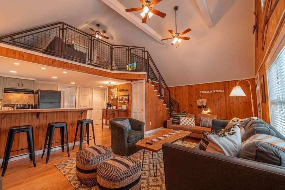 Step into luxury with our spacious sunroom, featuring a stunning log table and an inviting couch perfect for relaxation. Enjoy high ceilings and a modern loft vibe, complemented by a mini bar for your convenience. 
