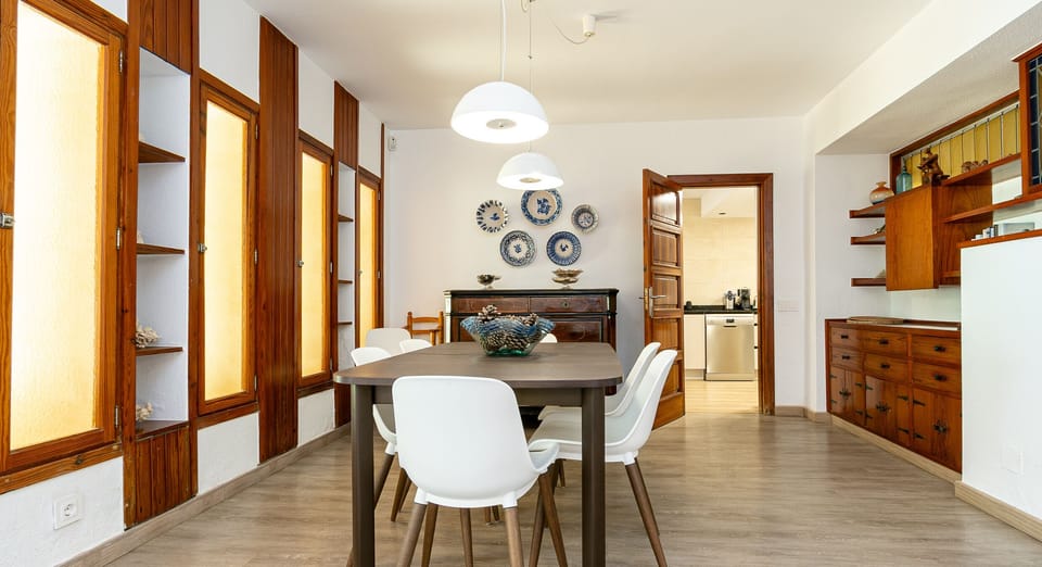Spacious dining room with wooden table, white chairs and classic style cabinets.