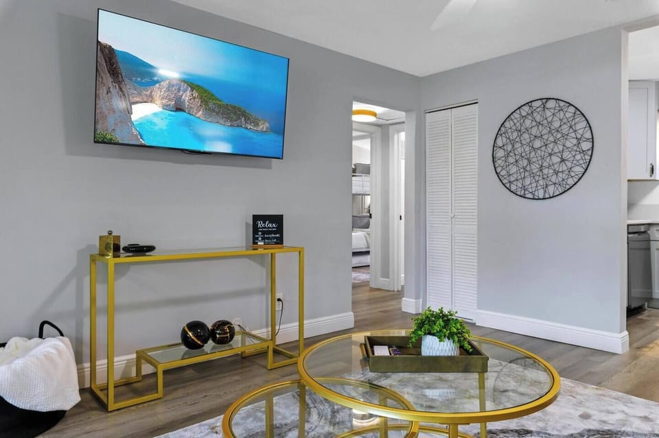 Flat screen TV and view to the kitchen and second bedroom.